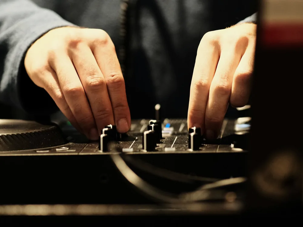 Mains réglant les faders d'une table de mixage DJ