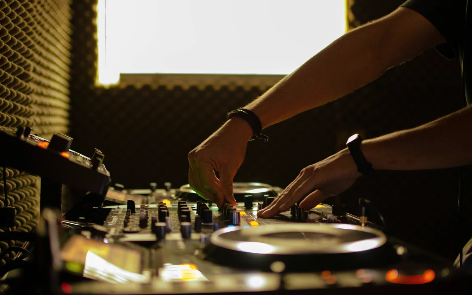Mains sur une platine et une table de mixage dans une salle traitée acoustiquement